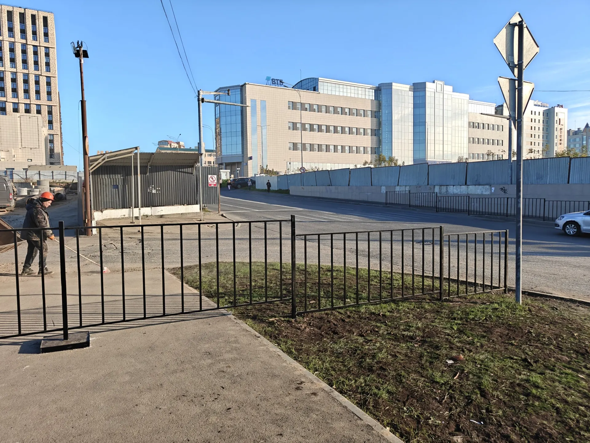 Ограждения возле центра города перекрыли подход к пешеходному переходу, и горожане вынуждены обходить стройплощадку по дороге; похожие проблемы ранее возникали на других проектах застройки.